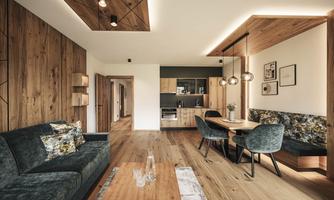 A modern living room with wooden paneling and stylish furnishings. The dining area is connected to a cozy seating area and a well-equipped kitchen.