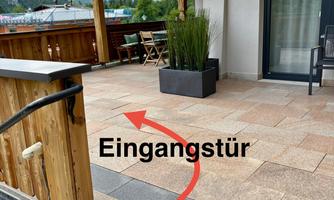 An inviting outdoor area with an entrance door and a key box. The successful design offers space for furniture and plants.