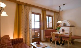 A cozy living space with a sofa and a dining table. Large windows let in plenty of light, and the curtains create an inviting atmosphere.