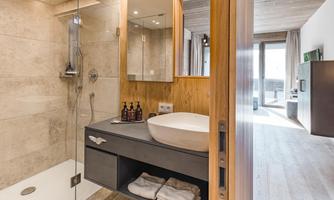 A modern bathroom with a shower and an elegant sink. Bright wood and stone surfaces create an inviting atmosphere.