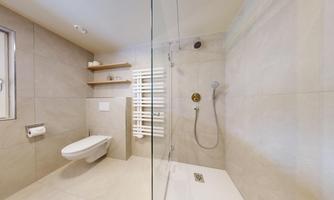 A modern bathroom with a glass shower and a wall-mounted toilet. The walls are bright, and the space feels clean and inviting.