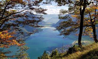 A picturesque landscape with a clear lake and autumn trees. The mountains in the background create a beautiful backdrop.