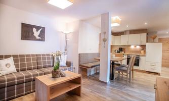 A modern living kitchen with a cozy sofa and a dining table. There is a bright and friendly atmosphere.