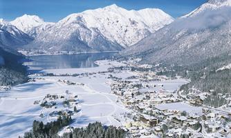 A winter landscape with snow-covered mountains and a lake. The village is picturesque in the valley between the mountains.