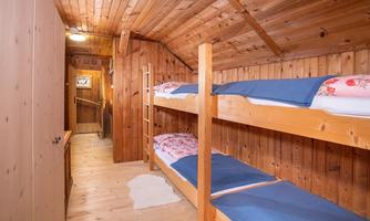 A simple room with two wooden bunk beds. The walls and ceiling are made of wood, and the room has a cozy atmosphere.