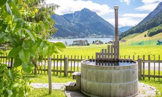 A wooden barrel with water in a picturesque landscape. In the background, mountains and a lake can be seen.