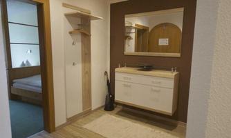 A bright hallway with a modern design style. Subtly lit, featuring a mirror and a practical piece of furniture.