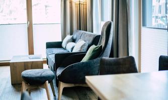 A modern living room with a comfortable sofa and a small table. Large windows let in plenty of light and create an inviting atmosphere.
