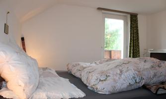 A cozy bedroom with a bed and fresh bedding. The room has a window with a view of the outdoors and a hint of natural light.