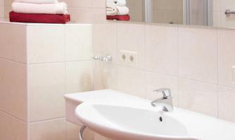 A modern bathroom with a sink and fresh towels. The walls are in light colors.