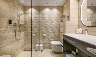 A modern bathroom with a walk-in shower and elegant, bright tiles. The fixtures include a sink and a toilet in a pleasing design.