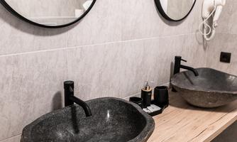 A modern bathroom with two stone sinks and mirrors. The wooden countertop adds a natural touch.