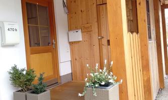 An inviting entrance area with a wooden door and a canopy. Next to the door are two flower pots.
