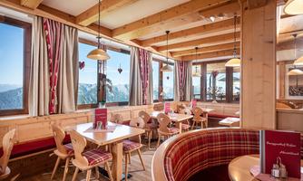 An inviting restaurant with warm wooden interiors and cozy seating. Large windows provide a view of the mountains.