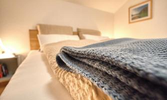 A cozy bedroom with a double bed and a blue blanket. Soft light creates a relaxed atmosphere.