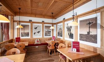 A cozy restaurant with wooden decor and wooden tabletops. Photos of animals and rural motifs hang on the walls.