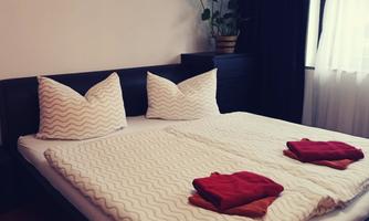A cozy bedroom with a large bed and decorative pillows. On the bedspread, there are some folded towels.
