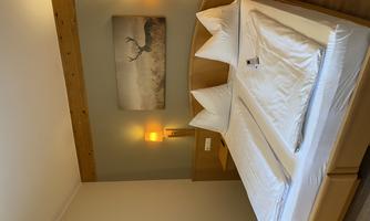 A cozy bedroom with a double bed and two nightstands. A picture of a deer in a landscape hangs on the wall.