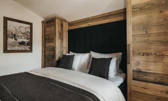 A comfortable bedroom with a large bed and wood-paneled walls. The decorative elements give the room a warm and inviting atmosphere.
