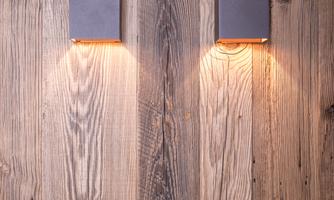 Two modern wall lamps on a wooden wall. The warm light sources create an inviting atmosphere.