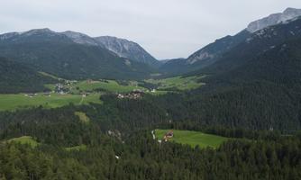 A picturesque landscape with green meadows and mountains in the background. Small villages are nestled in the gentle hilly landscape.