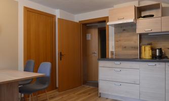 Modern kitchen with wooden cabinets and a dining area. The room is bright and inviting.