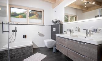 A modern bathroom with a bathtub, a shower, and a large mirror. The decor is in neutral colors and appears bright and inviting.