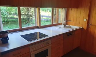 A modern kitchen with wooden paneling and large windows.