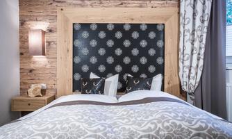 A cozy bedroom with a wooden frame bed and stylish wall paneling. The neutral colors and modern design create an inviting atmosphere.