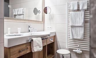 A modern bathroom with a sink, mirror, and wooden cabinets. Towels hang on a towel rack.