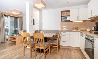 A modern kitchen with a wooden dining area. Bright colors and plenty of daylight create an inviting atmosphere.
