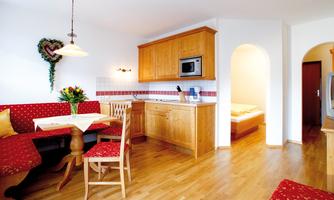 A cozy kitchen with wooden cabinets and red upholstery. A dining area with a table and chairs invites you to linger.