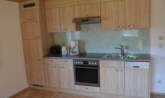 A modern kitchen with wooden cabinets and stainless steel appliances. It is well equipped with a stove, a sink, and a refrigerator.