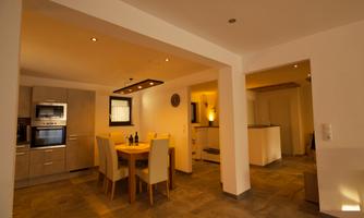 A modern kitchen with a dining area. The room is bright and inviting, with elegant furniture and warm lighting.