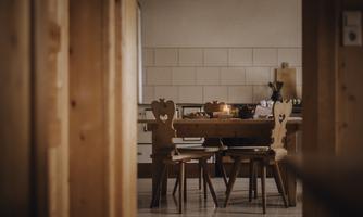 A cozy kitchen with a wooden table and chairs. The table is set and there is a warm, inviting atmosphere.