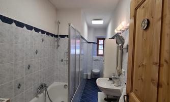 A modern bathroom with a bathtub, shower, and sink. It has bright tiles and a wood trim.