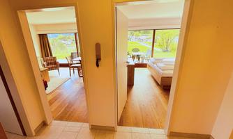 An inviting hallway with two open doors, each leading to separate rooms. On the left side is a cozy living area, while the right side shows a bedroom.