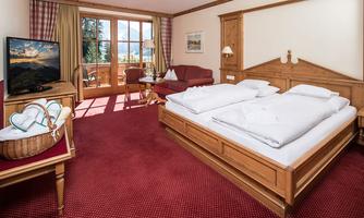 A cozy hotel room with a double bed and a television. Large windows provide a view of the surroundings and let in plenty of natural light.