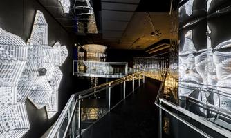 A modern interior with bright, geometric patterns on the wall. An elegant staircase leads to a well-lit area.