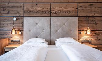 A modern bedroom with two beds and a stylish wooden interior. The soft lighting creates a cozy atmosphere.
