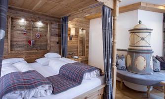 A cozy bedroom with a wooden frame bed and warm textiles. The rustic decor creates an inviting atmosphere.