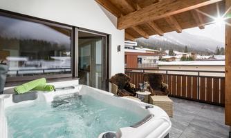 A beautiful balcony with a hot tub and a view of the mountains. Cozy seating and a relaxing atmosphere invite you to linger.