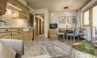 A cozy living kitchen with wooden furniture and modern design. The room is bright and inviting, with a dining area and a window view outdoors.