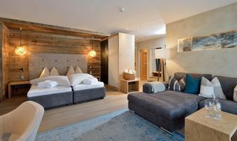 A modern bedroom with wooden accents and a cozy sofa. The room design is bright and inviting.