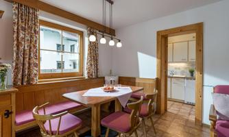 A cozy dining area with a wooden table and colored chairs. The window lets in plenty of natural light and offers a view of the outside world.