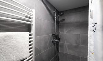 A modern shower with gray tiles and a towel rack. The furnishings are minimalist and elegant.