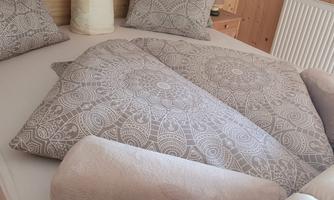 A cozy bed with decorative pillows and a pretty blanket. The warm wood paneling creates an inviting atmosphere.