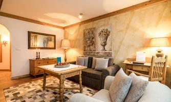 A cozy living room with a sofa and a table. The walls are decorated and there is soft lighting.