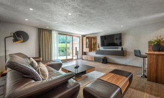 A modern living room with comfortable leather furniture and a large window. The space is bright and inviting, with stylish decorations.