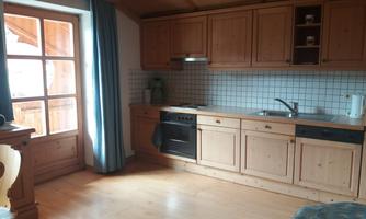 A cozy kitchen with wooden cabinets and a bright floor. The windows let in plenty of daylight.
